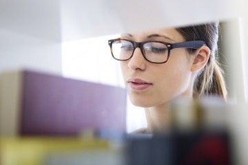 Studentin sucht nach einem Buch in der Bücherei